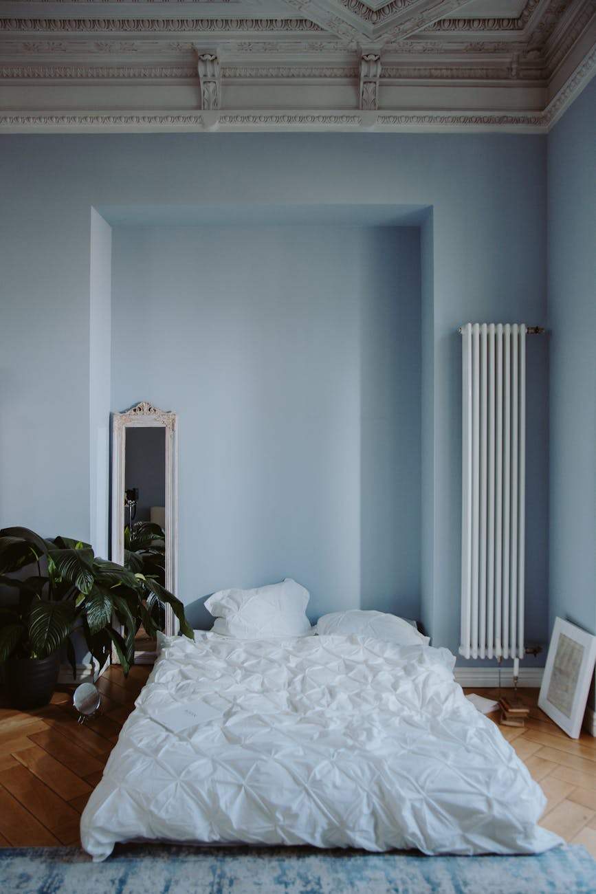 white bed linen near light blue wall