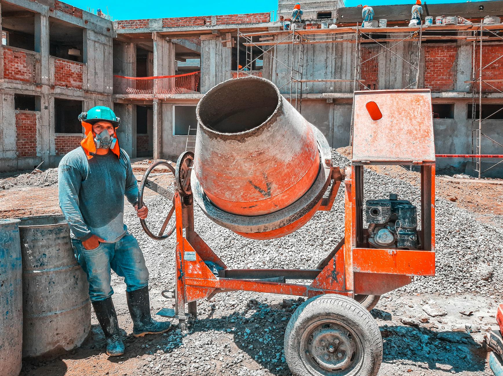 worker with gas mask operating concrete mixer